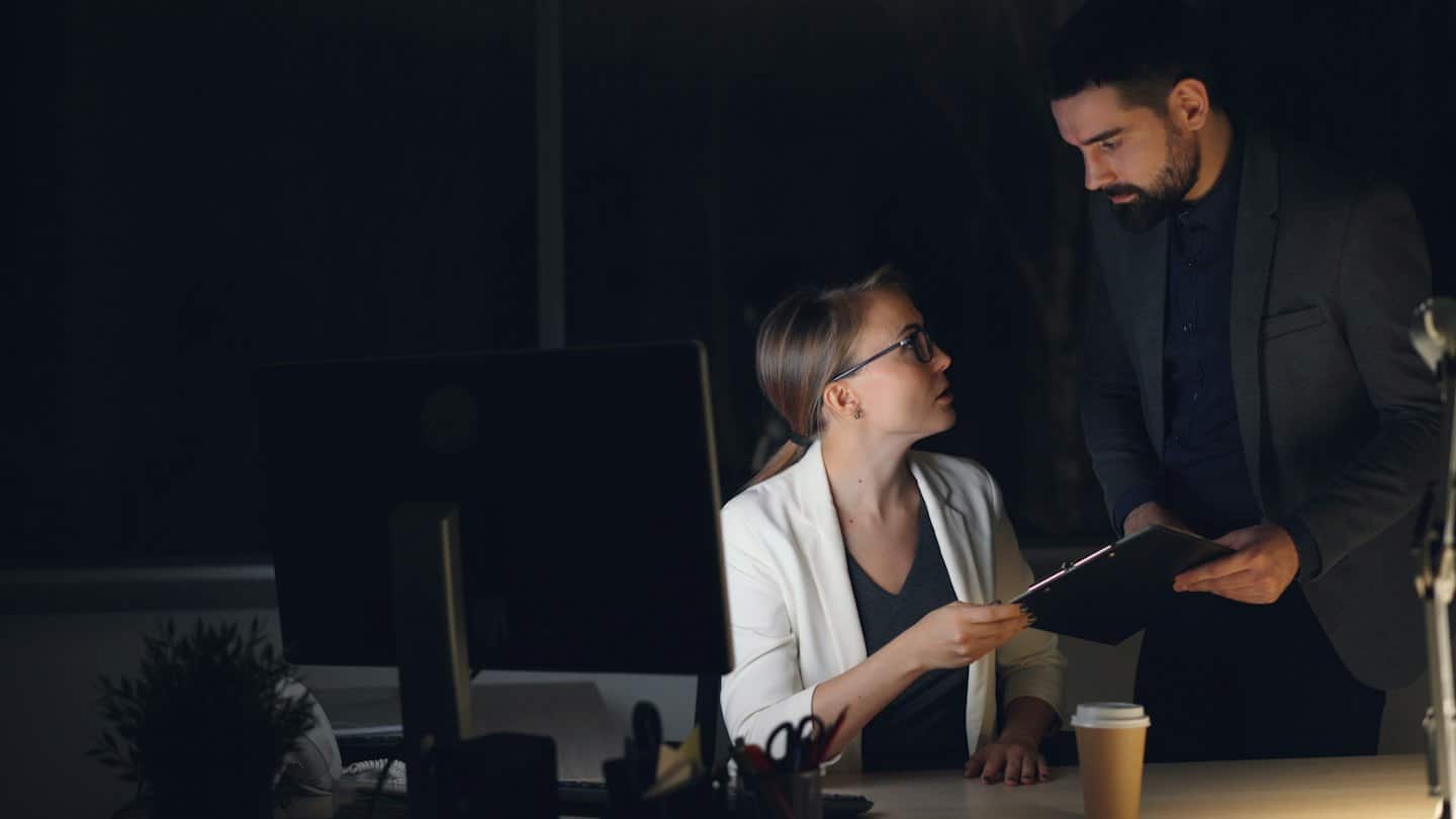 Professionnels d'affaires discutant de documents à un bureau tard le soir.